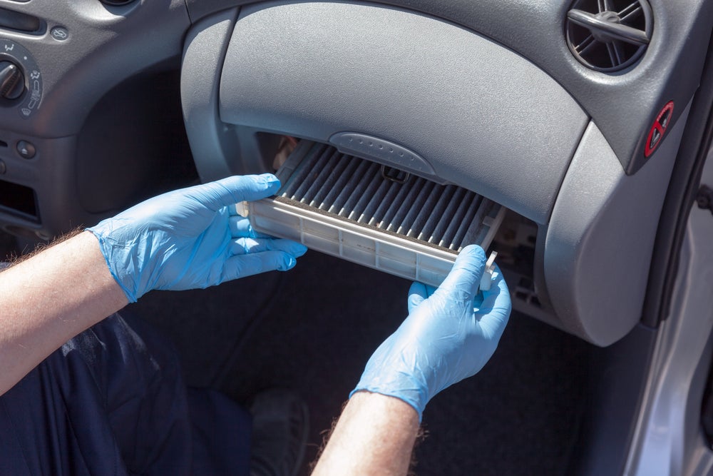 Cabin Air Filter being replaced by technician with blue gloves on