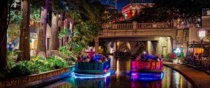 Two passenger boats on the river headed under a bridge at the riverwalk in San Antonio, TX.