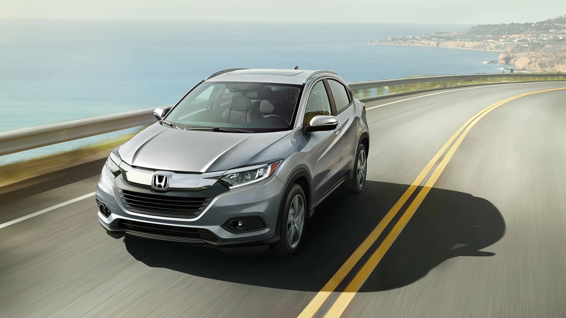 Grey 2023 Honda HR-V driving on a road near a body of water