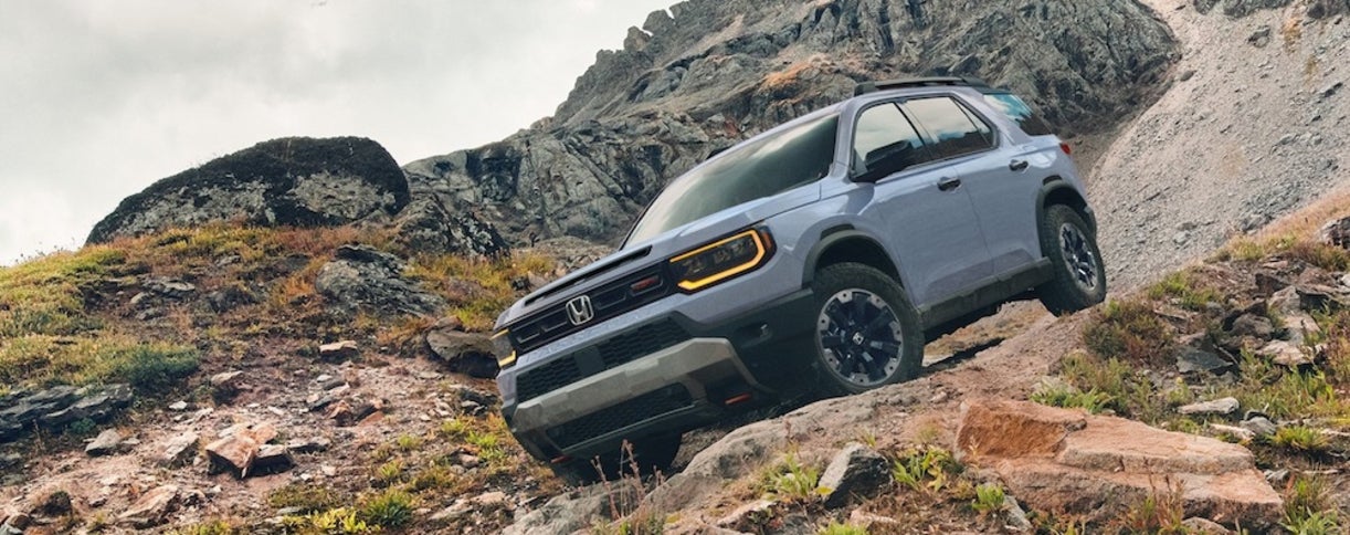 A light-colored Honda passport on a steep rugged incline